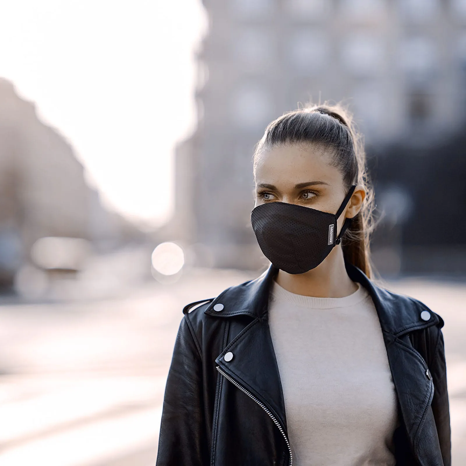 Kobieta w czarnej masce PureAir na miejskiej ulicy